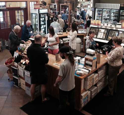 A busy store with customers at the counter, browsing products and interacting with staff in a warm, inviting atmosphere.