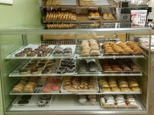 A display case filled with various types of donuts, including glazed, chocolate, and sprinkled varieties.