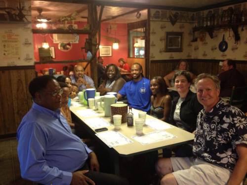 A group of people sitting around a table in a casual restaurant, smiling and enjoying their time together.