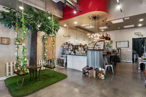 A cozy café interior featuring swings, greenery, and a stylish counter with hanging lights and decorative elements.
