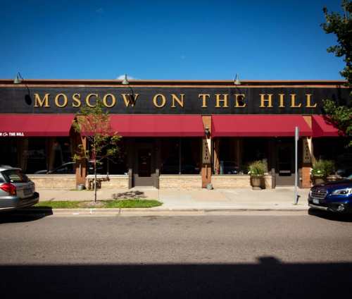 Exterior of "Moscow on the Hill" restaurant with red awnings and a clear blue sky.