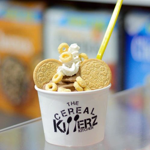 A cup filled with cereal, cookies, and a yellow straw, set against a colorful background.