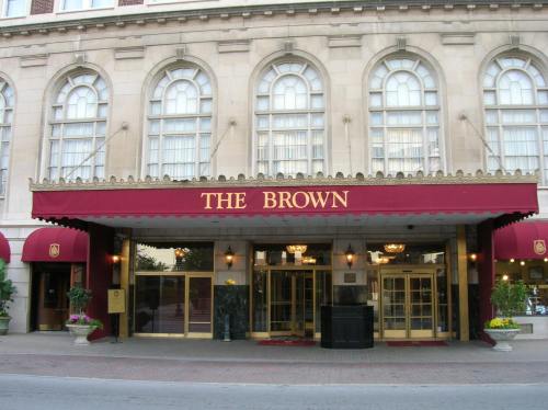 Entrance of The Brown Hotel, featuring a red awning and elegant architecture with large windows.