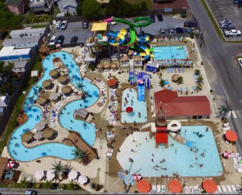 Aerial view of a vibrant water park featuring pools, slides, and lounging areas surrounded by greenery.