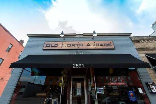 Front view of Old North Arcade building with a sign, awning, and colorful storefront under a blue sky.