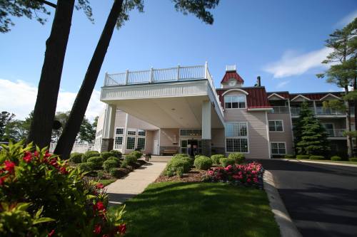 A hotel entrance surrounded by greenery and colorful flowers, with a clear blue sky in the background.