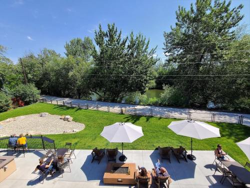 A sunny outdoor area with umbrellas, seating, and a view of trees and a river in the background.