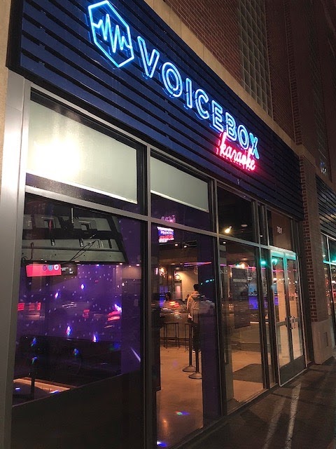 Exterior of Voicebox Karaoke with neon signage, showcasing a lively atmosphere at night.
