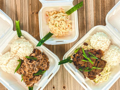 Three takeout containers with rice, pulled meat, and a side of macaroni salad, garnished with green onions.