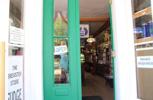 A view through a green door into a store, with an "Open" sign and various items visible inside.