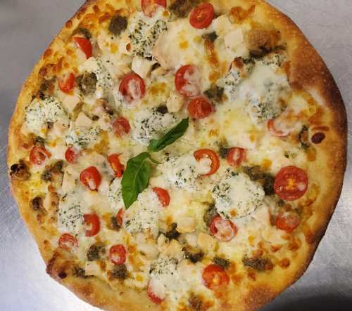 A freshly baked pizza topped with chicken, cherry tomatoes, basil, and a mix of cheeses on a golden crust.