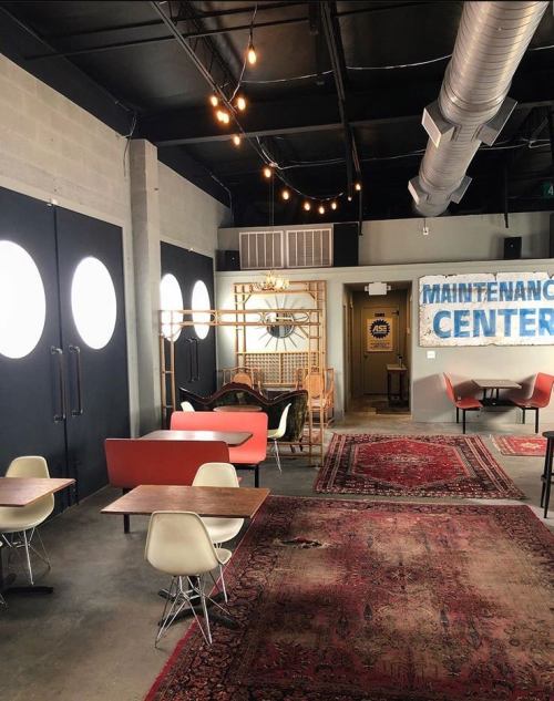 A modern interior with circular windows, cozy seating, and a "Maintenance Center" sign on the wall.