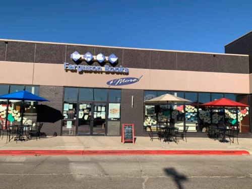 Exterior of Ferguson Books with colorful umbrellas, outdoor seating, and large windows displaying book-themed decorations.