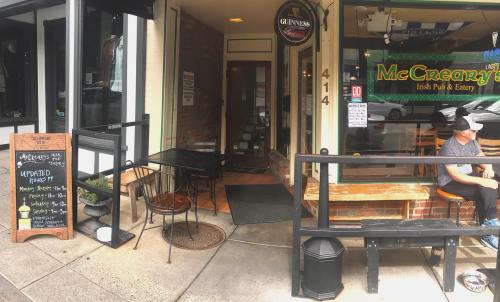 Exterior view of McCreary's Irish Pub & Eatery, featuring outdoor seating and a chalkboard menu.