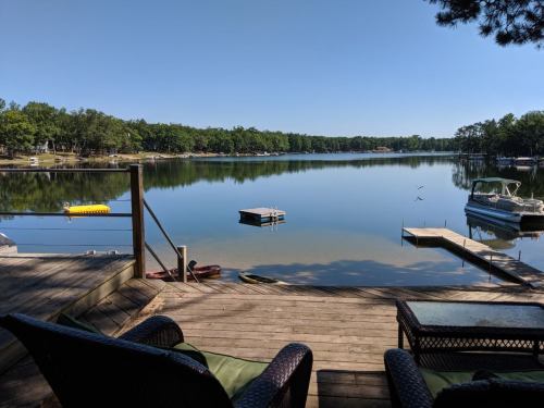 A serene lake view from a wooden deck, featuring boats and lush greenery under a clear blue sky.