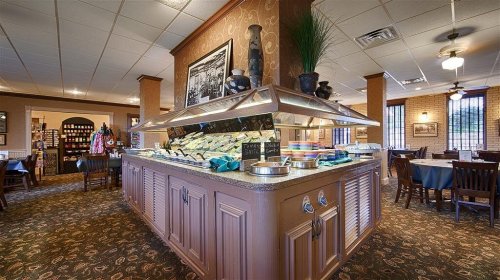 A cozy restaurant interior featuring a buffet station with various dishes and a warm, inviting atmosphere.