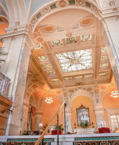 Elegant interior of a grand hall featuring ornate ceilings, stained glass, and marble details.