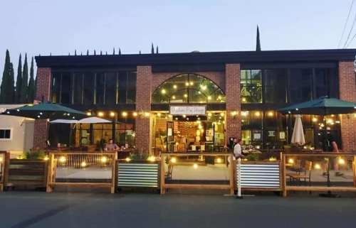 A cozy restaurant with outdoor seating, string lights, and a welcoming atmosphere at dusk.