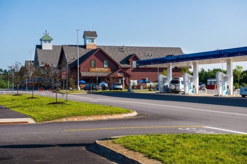 A gas station with pumps in front of a large, rustic-style building under a clear blue sky.