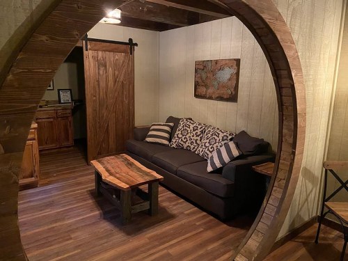 Cozy living room with a circular wooden arch, featuring a sofa, coffee table, and rustic decor.