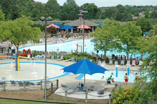 Aerial view of a vibrant pool area with umbrellas, lounge chairs, and people enjoying the water on a sunny day.