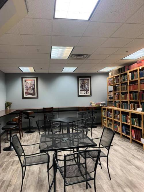 A cozy library space with a glass table, chairs, and bookshelves filled with books on the walls.
