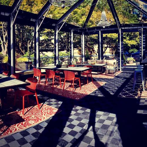 A bright indoor space with red chairs, patterned rugs, and large windows overlooking greenery.
