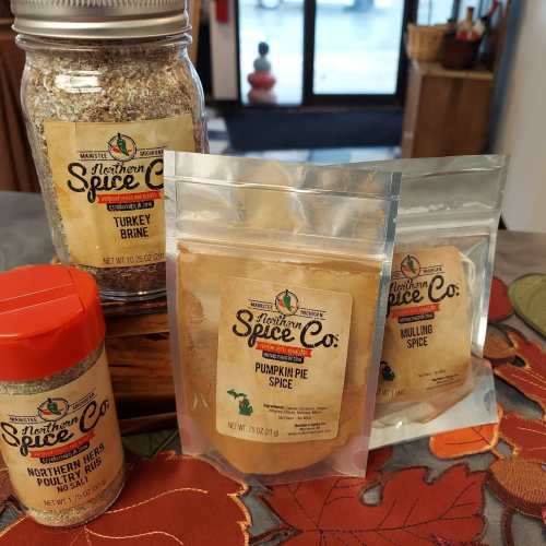 A collection of spice packets and jars, including turkey brine, pumpkin pie spice, and northern herb rub, on a table.