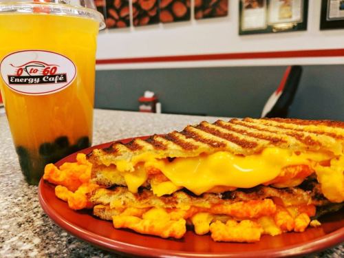 A plate with a grilled cheese sandwich and a drink in a cup, featuring orange juice and bubbles.
