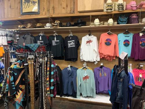 A retail display featuring various clothing items, including t-shirts and sweatshirts, alongside hats and accessories.