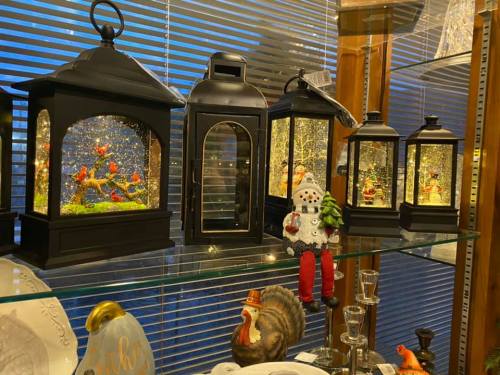 A display of decorative lanterns with snowy scenes, alongside a snowman figurine and other decorative items.