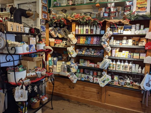 A cozy shop display featuring shelves of various products, including teas, soaps, and snacks, decorated for the holidays.