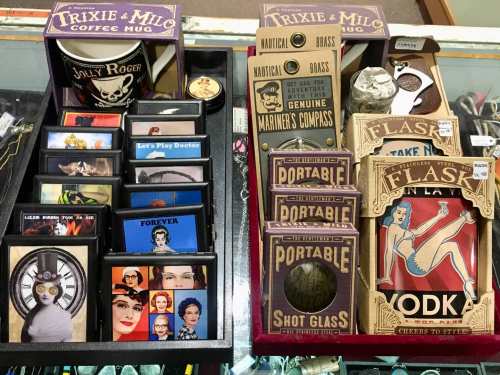 A display of novelty items including mugs, shot glasses, and flasks with various designs and themes.