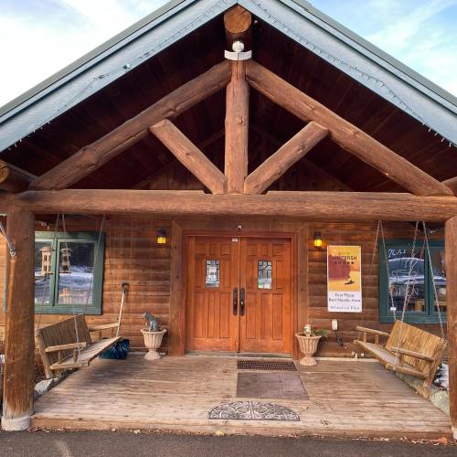 A rustic wooden building with a large entrance, featuring two doors and benches on either side.