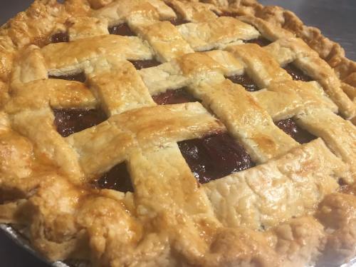 A freshly baked lattice-top pie with a golden crust and a rich, dark filling peeking through the lattice.