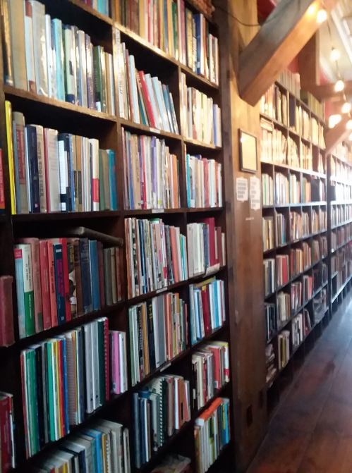 A cozy library with wooden shelves filled with colorful books, illuminated by warm lights.