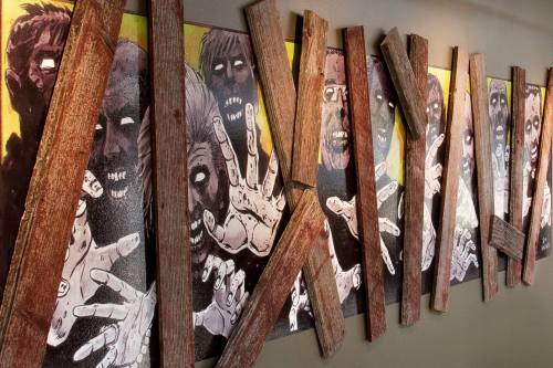 A wall display featuring zombie artwork surrounded by wooden planks, creating a spooky atmosphere.