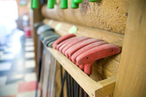 A wooden shelf displaying red climbing holds, with various other climbing gear in the background.