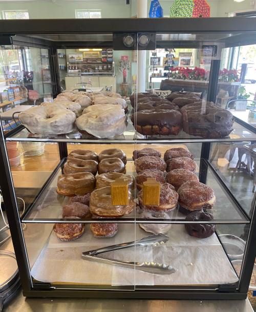 A display case filled with various donuts, including glazed, chocolate, and cinnamon sugar varieties.