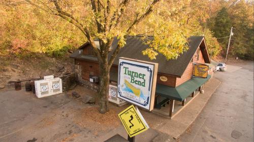 Aerial view of Turner Bend, a rustic building surrounded by autumn trees and a winding road sign nearby.