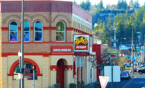 A brick building with "Billy's Restaurant" sign, featuring arched windows and nearby trees in a small town setting.