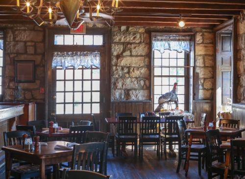 Cozy restaurant interior with wooden tables, stone walls, and a decorative rooster by the window.