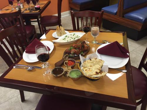 A dining table set with red napkins, wine glasses, and an array of Indian dishes, including naan and chicken.