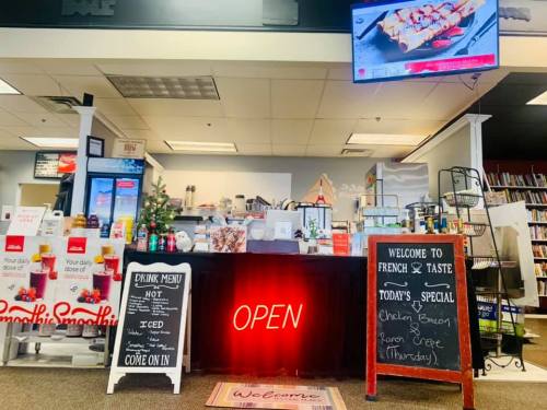 A cozy café counter with an "OPEN" sign, menu displays, and a TV showing daily specials.