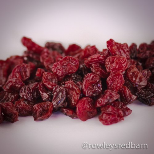 A close-up of dried cranberries, showcasing their rich red color and wrinkled texture.