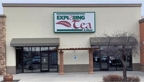 Storefront of "Exploring Tea & More," featuring a large sign and a covered entrance with decorative columns.