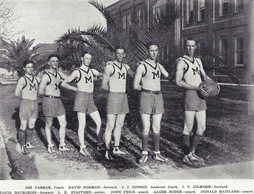 Black and white photo of six basketball players in uniforms, lined up outdoors with palm trees in the background.