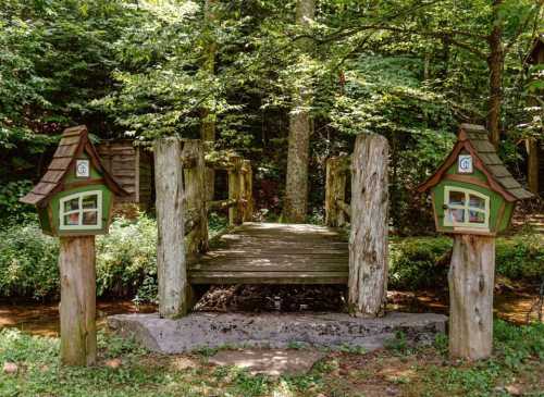 A wooden bridge surrounded by trees, with small green houses on either side.