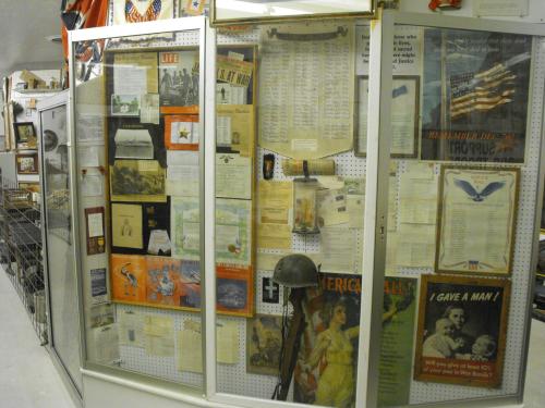 Display case filled with historical documents, posters, and artifacts, showcasing American history and military memorabilia.