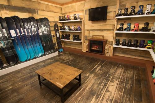 A cozy ski shop interior featuring snowboards, boots, and a small fireplace on a wooden floor.